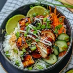 Sweet chili chicken rice bowl with lime, cucumbers, shredded carrots, and sesame seeds