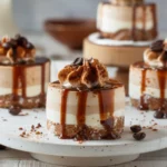 Close-up of mini coffee cheesecakes with espresso, layered with cream, topped with whipped frosting, chocolate drizzle, and coffee beans