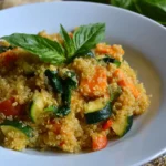 Quinoa casserole with zucchini, carrots, spinach, and fresh basil served in a white bowl